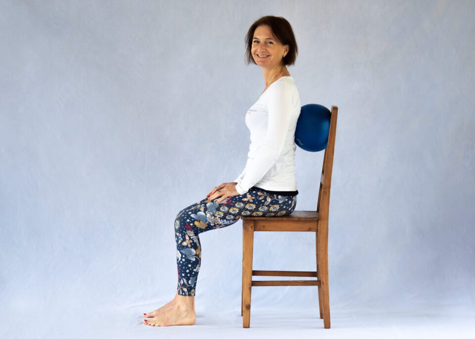 A woman sitting correctly at an office desk.