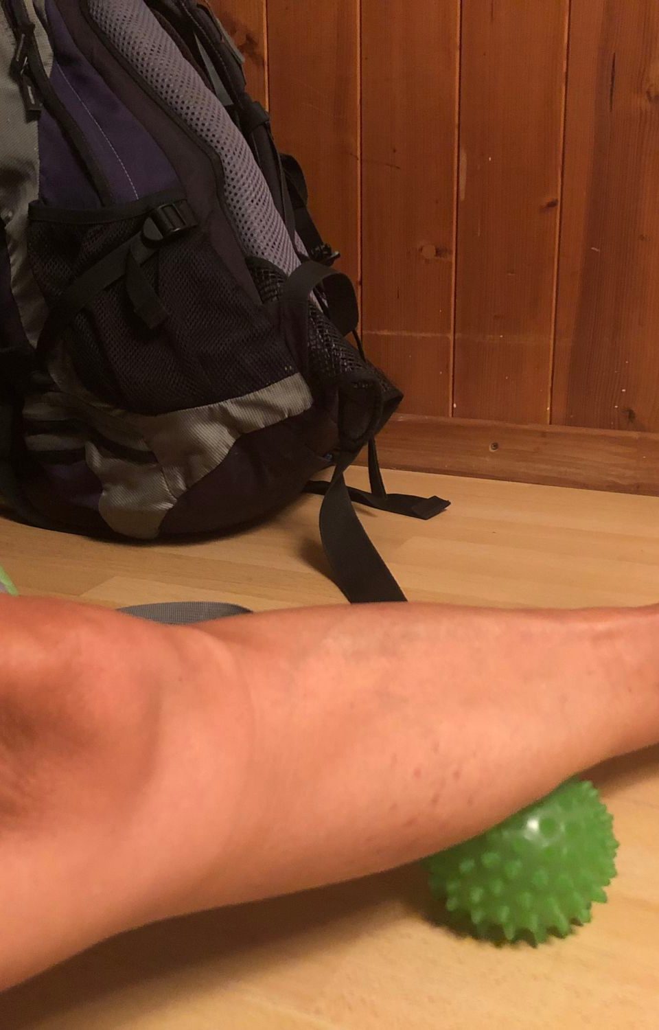 A woman using a foam ball for self-massage on her leg.