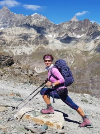 A hiker with a backpack looking at a mountain range