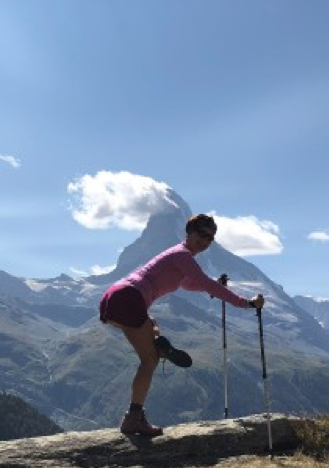 A hiker stretching their leg against a rock